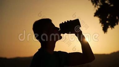 夕阳下，一个健康的年轻人背着<strong>太阳</strong>喝水的剪影<strong>缓缓</strong>移动